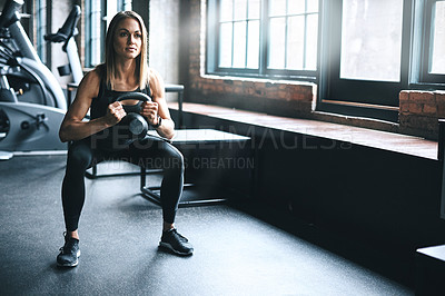 Buy stock photo Shot of a young woman working out with a kettle bell in a gym