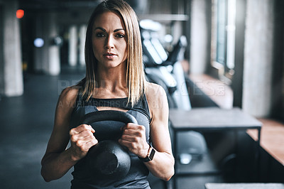 Buy stock photo Shot of a young woman working out with a kettle bell in a gym