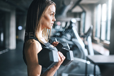 Buy stock photo Shot of a young woman working out with weights in a gym