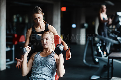 Buy stock photo Cropped shot of a mature woman lifting weights with a female instructor at the gym