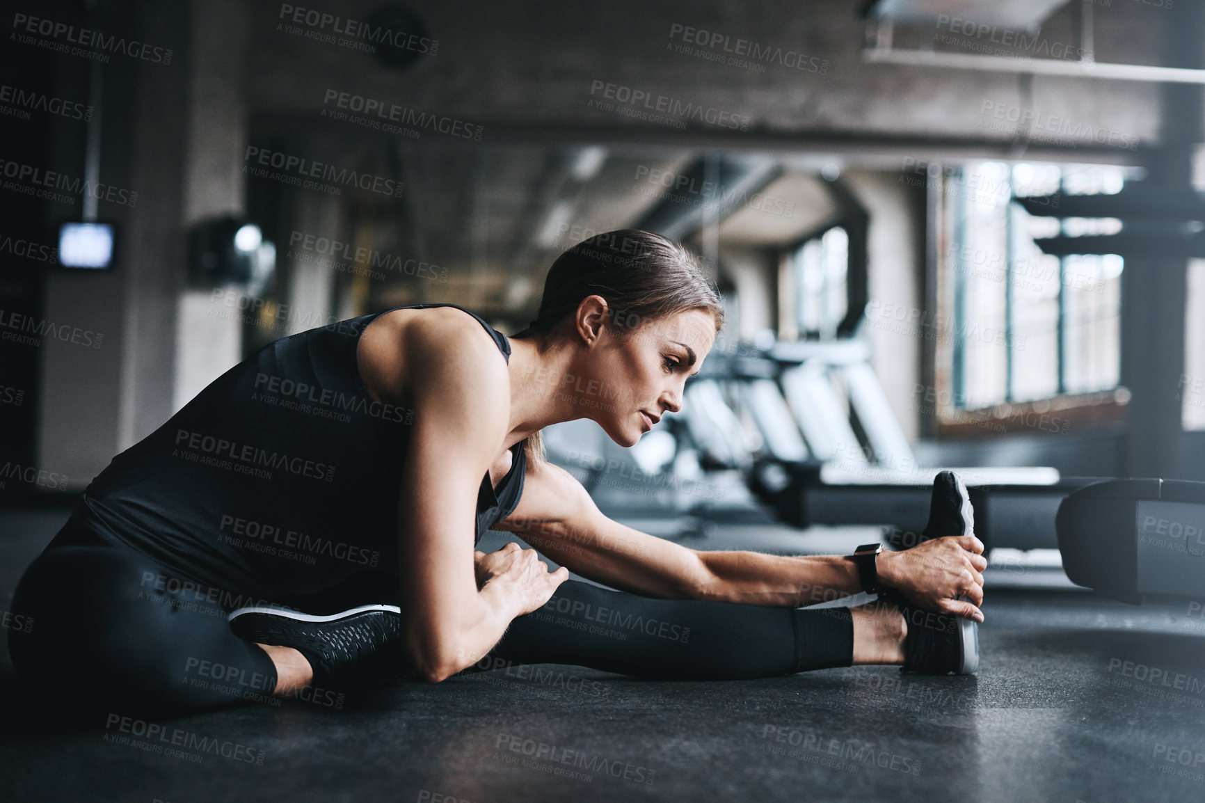 Buy stock photo Shot of an attractive young woman stretching during her workout in a gym