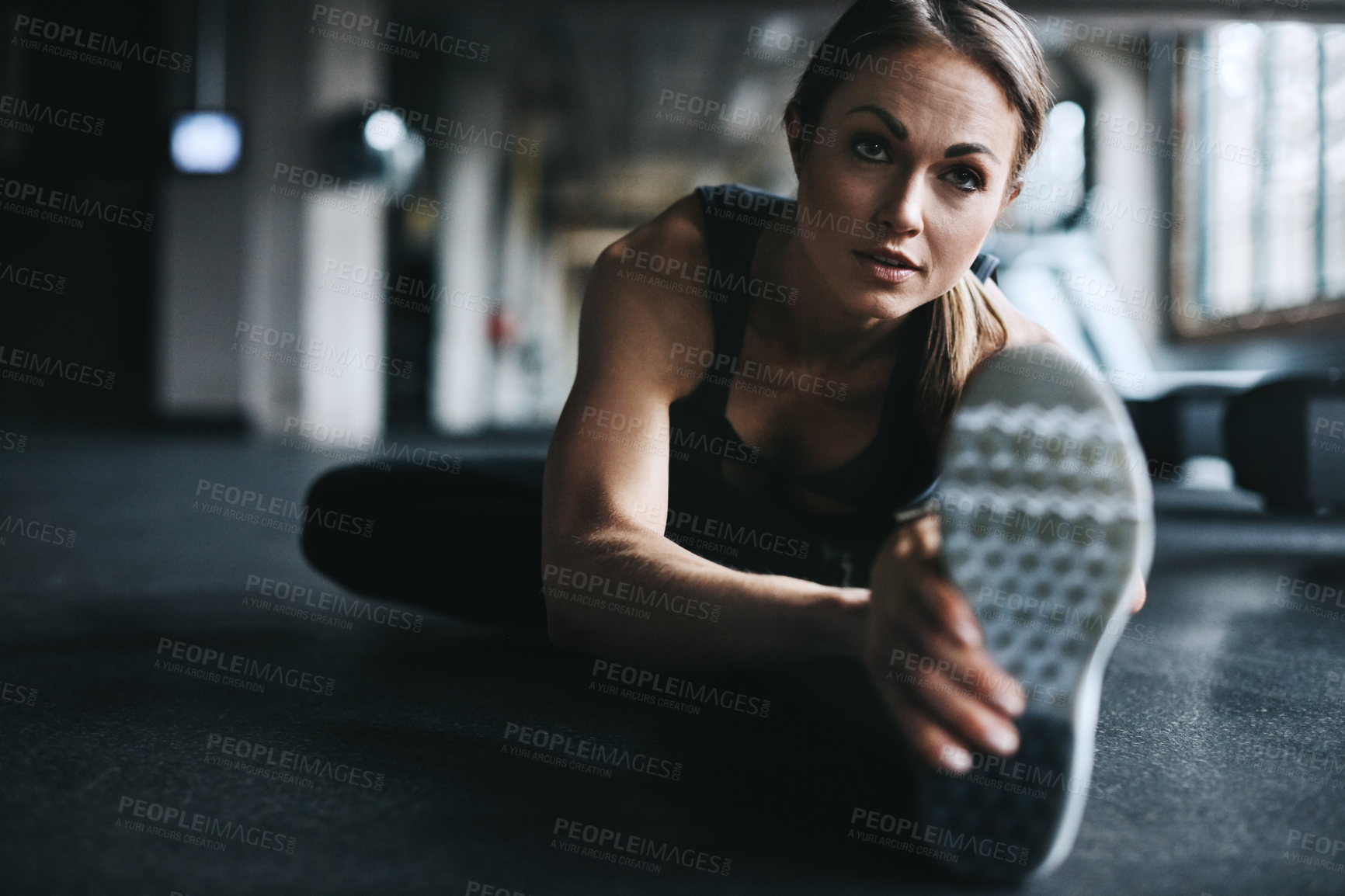 Buy stock photo Shot of an attractive young woman stretching during her workout in a gym