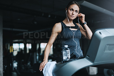 Buy stock photo Shot of an attractive young woman working out on a treadmill in a gym