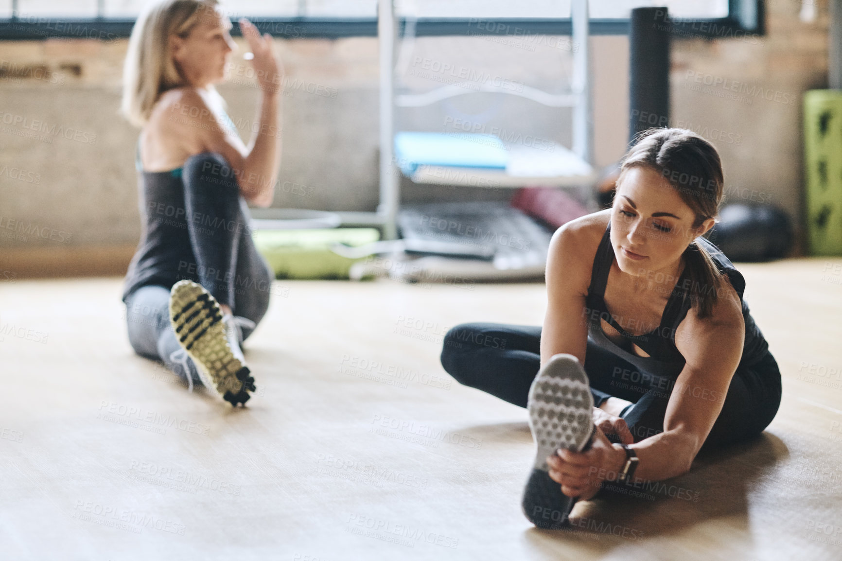 Buy stock photo Women, partner and stretching legs in gym, floor and together with coaching for training, fitness and health. People, friends and muscle with teamwork in warm up for exercise, workout and wellness