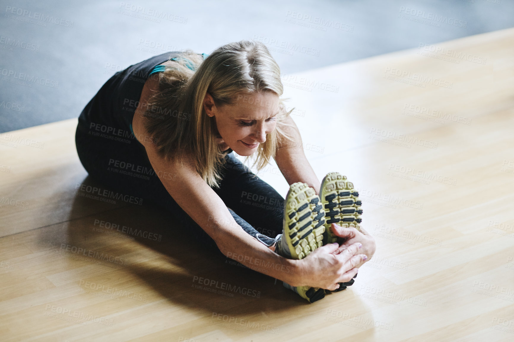 Buy stock photo High angle shot of an attractive mature woman stretching before her workout in the gym