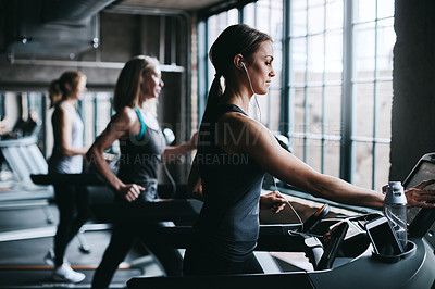 Buy stock photo Cropped shot of three attractive and athletic women working out in the gym