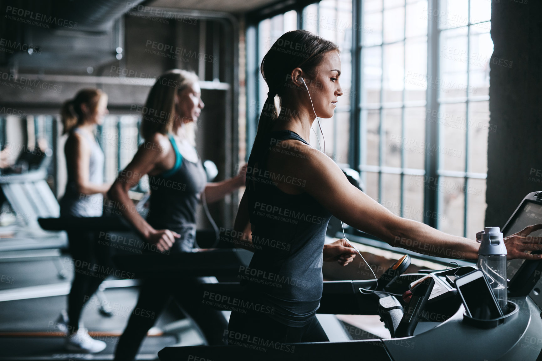 Buy stock photo Cropped shot of three attractive and athletic women working out in the gym