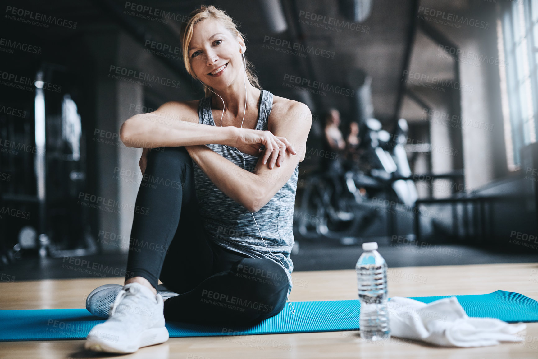 Buy stock photo Full length portrait of an attractive young woman listening to music while working out in the gym
