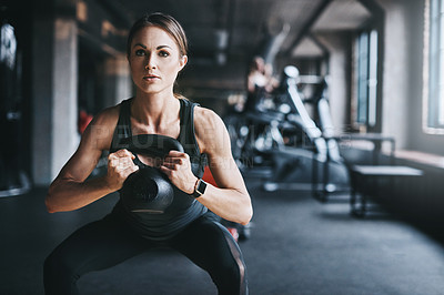 Buy stock photo Cropped shot of an attractive young woman working out with a kettle bell in the gym