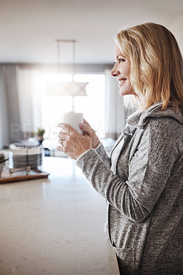 Buy stock photo Shot of a mature woman relaxing at home with a cup of coffee