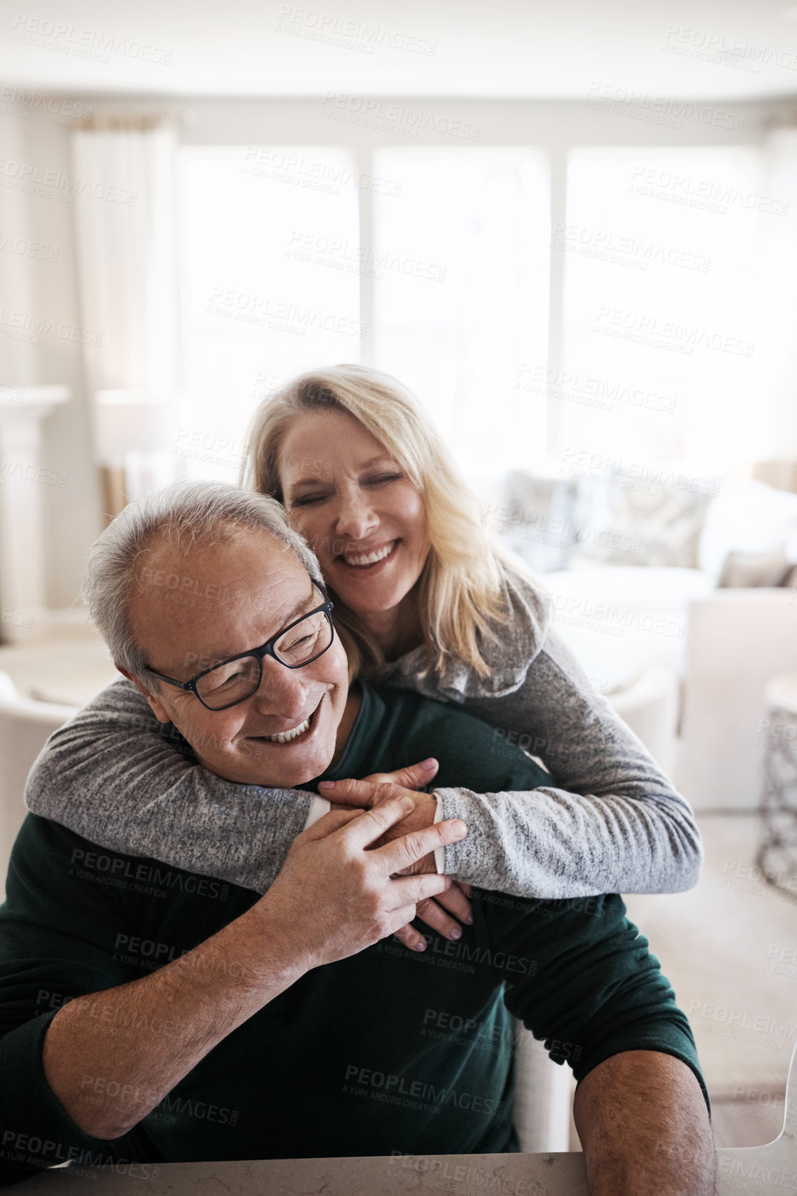 Buy stock photo Senior, couple and laughing with embrace in home for healthy marriage, commitment and bonding in retirement. Elderly, people and funny in house for joke, humor and romance with care in living room