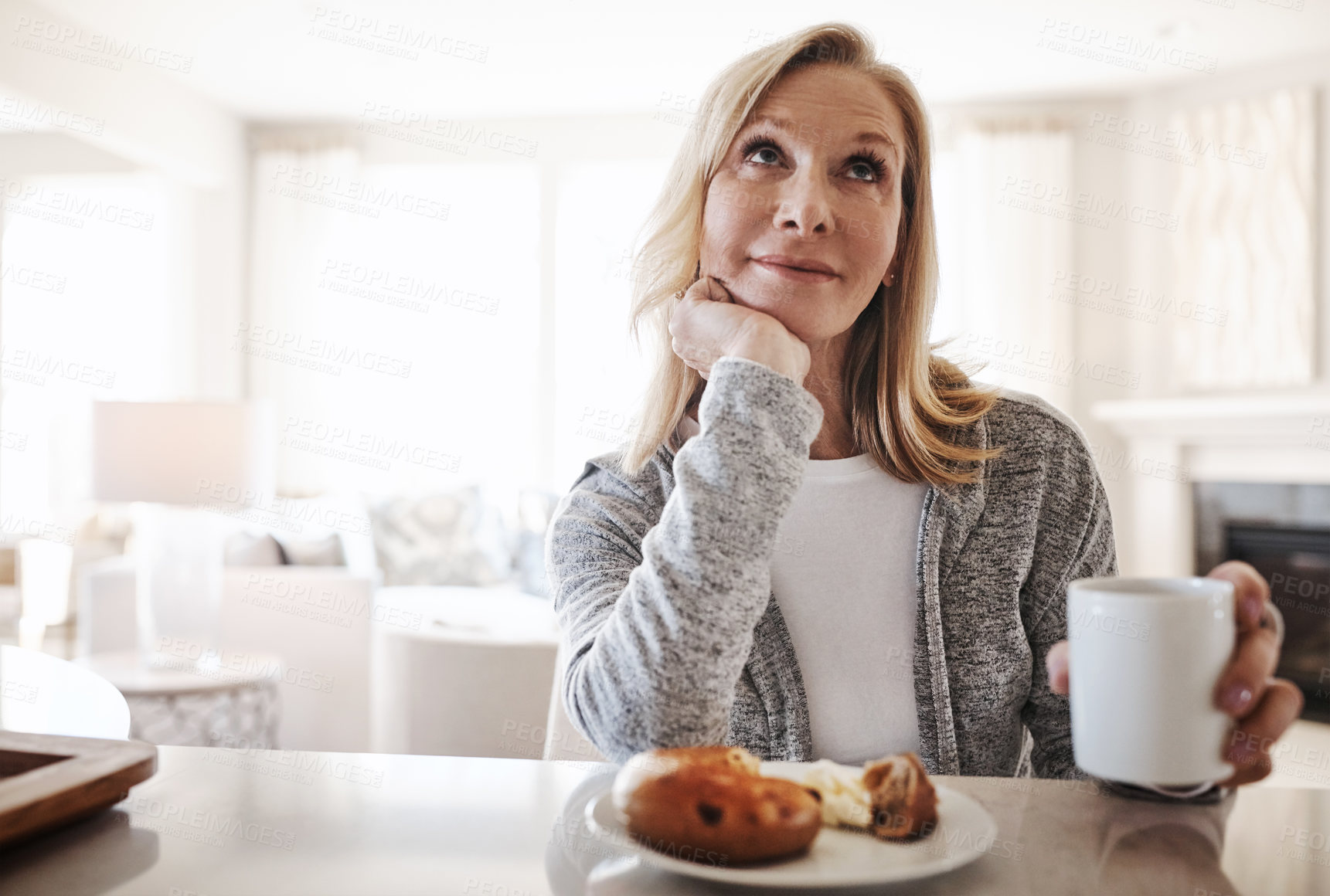 Buy stock photo Shot of a mature woman having coffee and a snack during a relaxed day at home