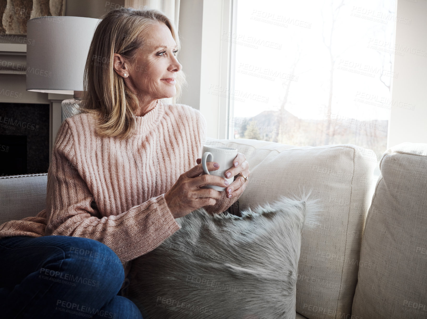 Buy stock photo Shot of a mature woman relaxing on the sofa at home with a cup of coffee