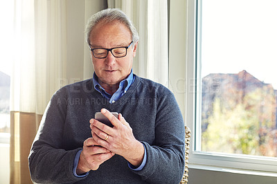 Buy stock photo Cropped shot of a senior man using a cellphone at home
