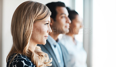 Buy stock photo Shot of a young businesswoman standing in an office with her colleagues in the background