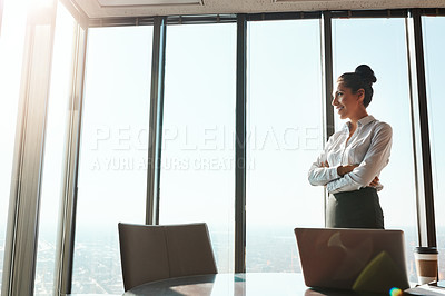 Buy stock photo Shot of a young businesswoman looking out the window in an office
