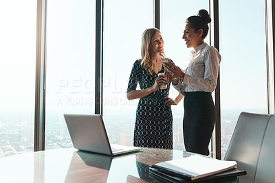 Buy stock photo Shot of a businesswoman showing her colleague something on her cellphone in an office