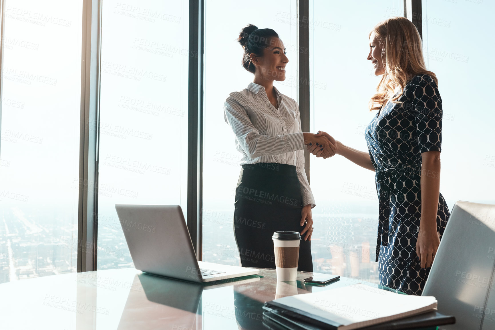 Buy stock photo Shot of two businesswomen shaking hands in an office