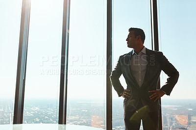 Buy stock photo Cropped shot of a handsome young businessman standing with his hands on his hips in the office