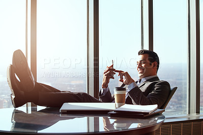 Buy stock photo Cropped shot of a handsome young businessman reading a text message while sitting in his office