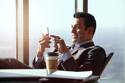 Buy stock photo Cropped shot of a handsome young businessman reading a text message while sitting in his office