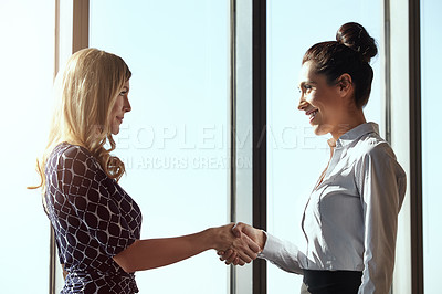 Buy stock photo Cropped shot of two young businesswoman shaking hands in their office