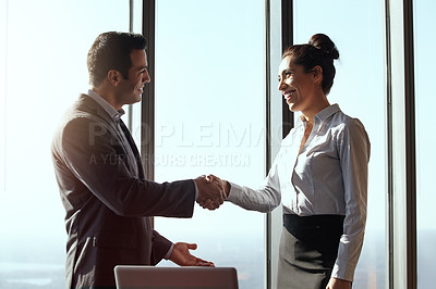 Buy stock photo Cropped shot of two young businesspeople shaking hands in their office
