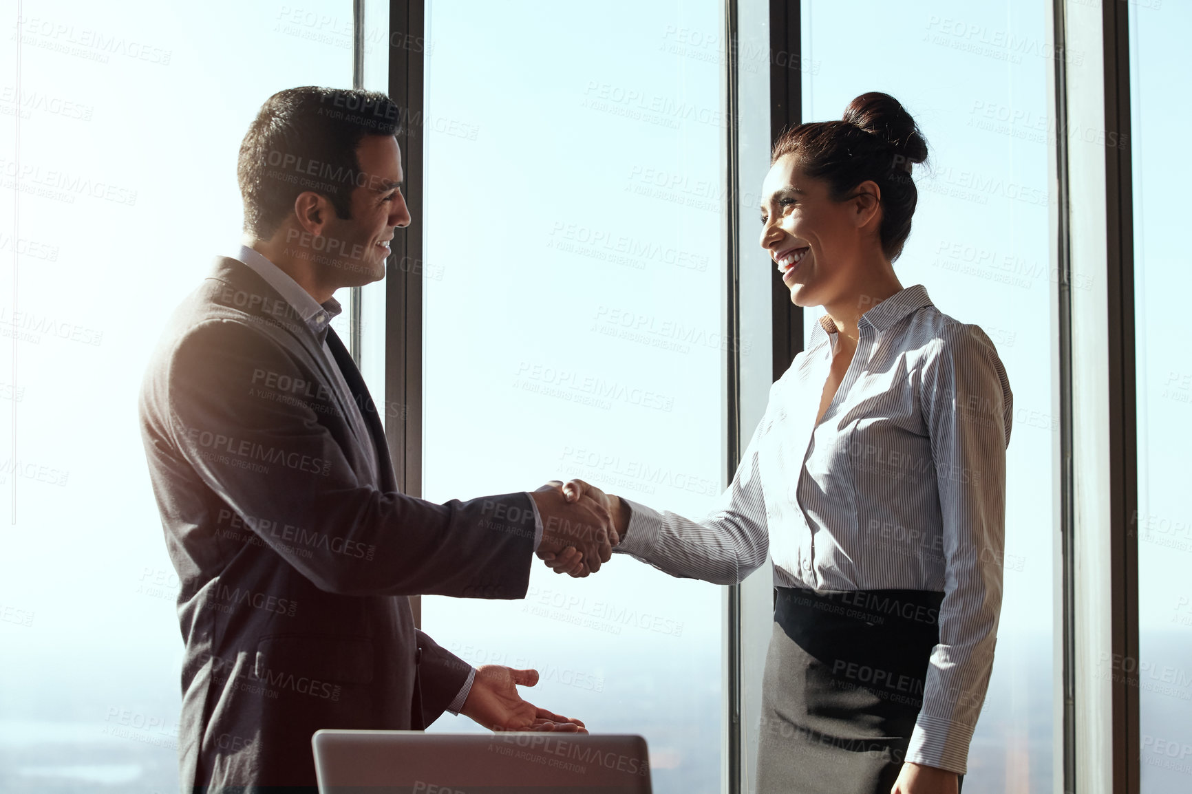 Buy stock photo Cropped shot of two young businesspeople shaking hands in their office