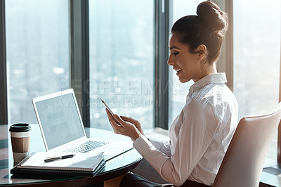 Buy stock photo Cropped shot of an attractive young businesswoman reading a text message while working in her office