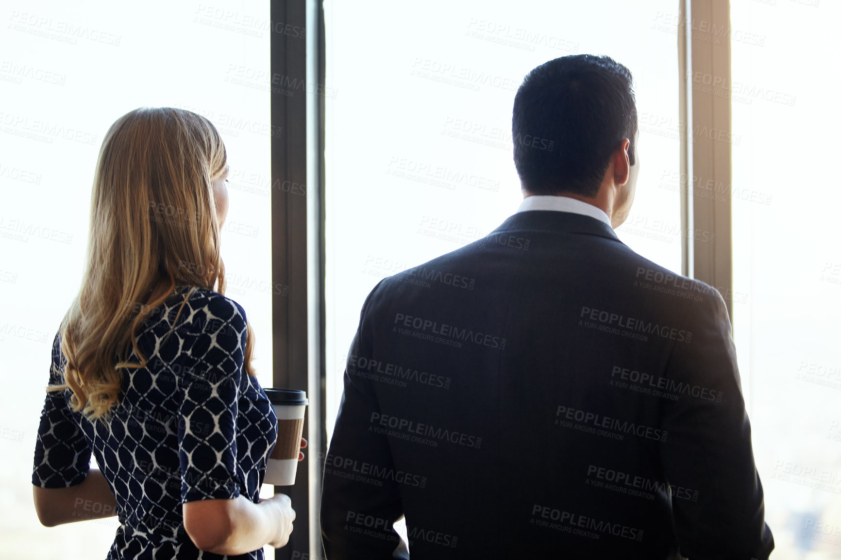 Buy stock photo Rearview shot of two young businesspeople standing in their office