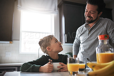 Buy stock photo Cropped shot of a young boy and his father having breakfast in the kitchen