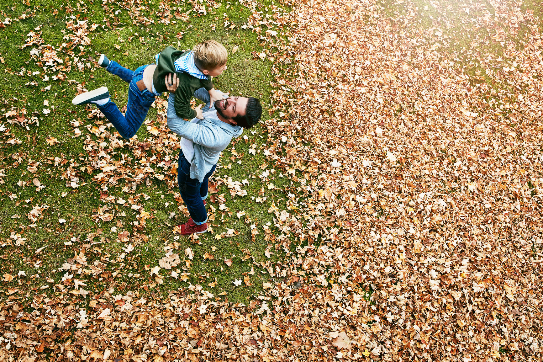 Buy stock photo Shot of a father and his little son playing in the autumn leaves outdoors