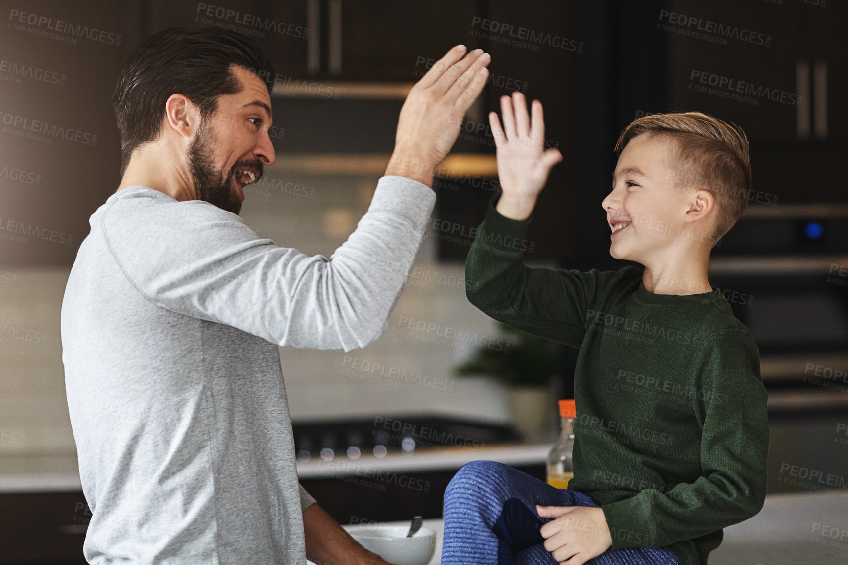 Buy stock photo Cropped shot of a handsome young man and his son high fiving in the kitchen