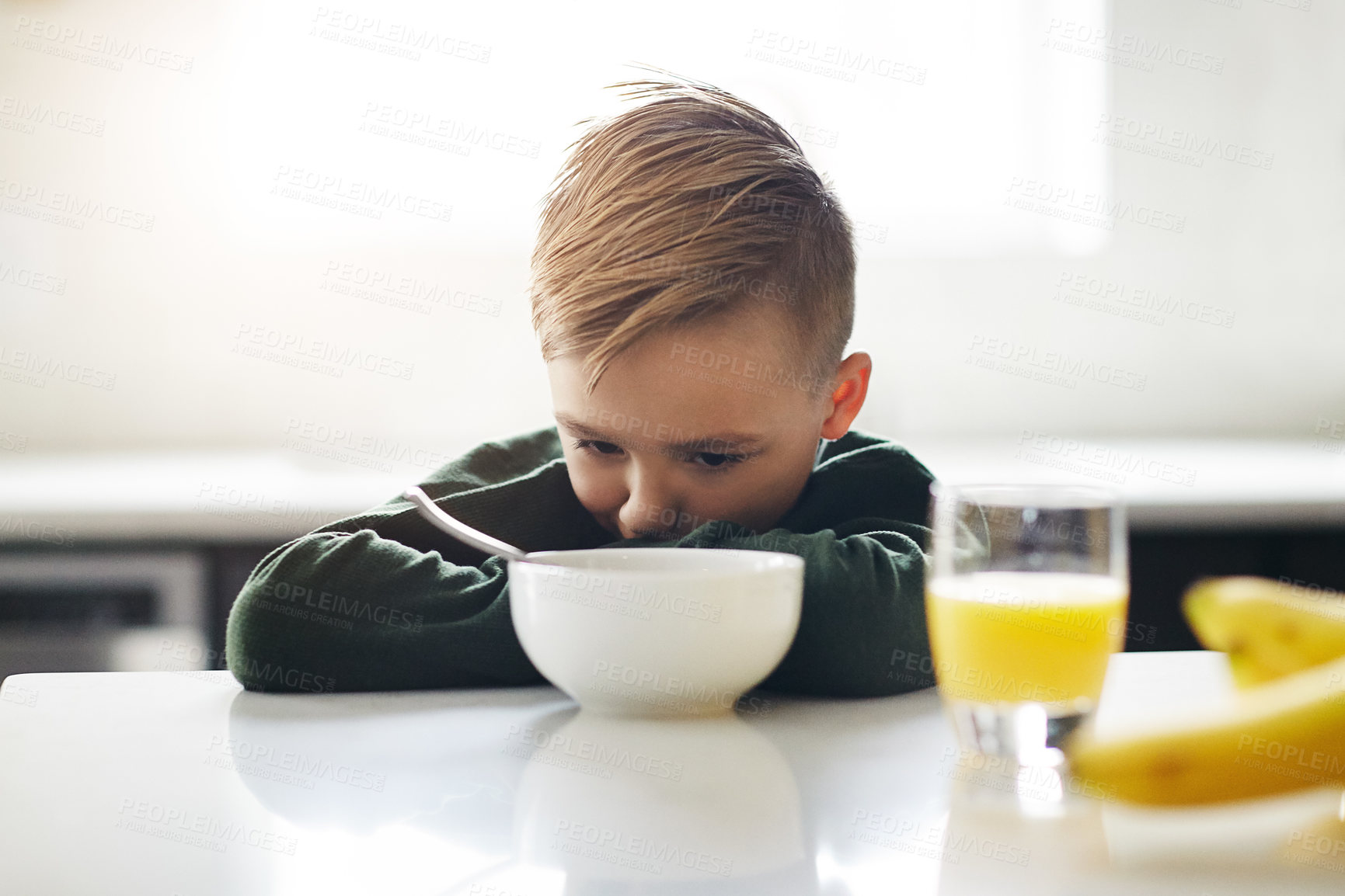 Buy stock photo Cropped shot of an adorable little boy having breakfast while sitting in the kitchen