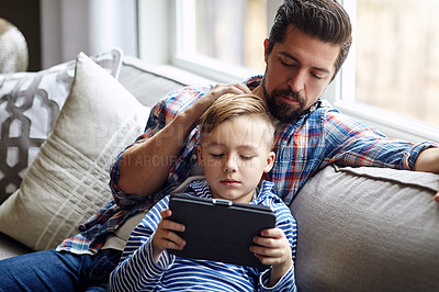 Buy stock photo Shot of a little boy using a digital tablet with his father at home