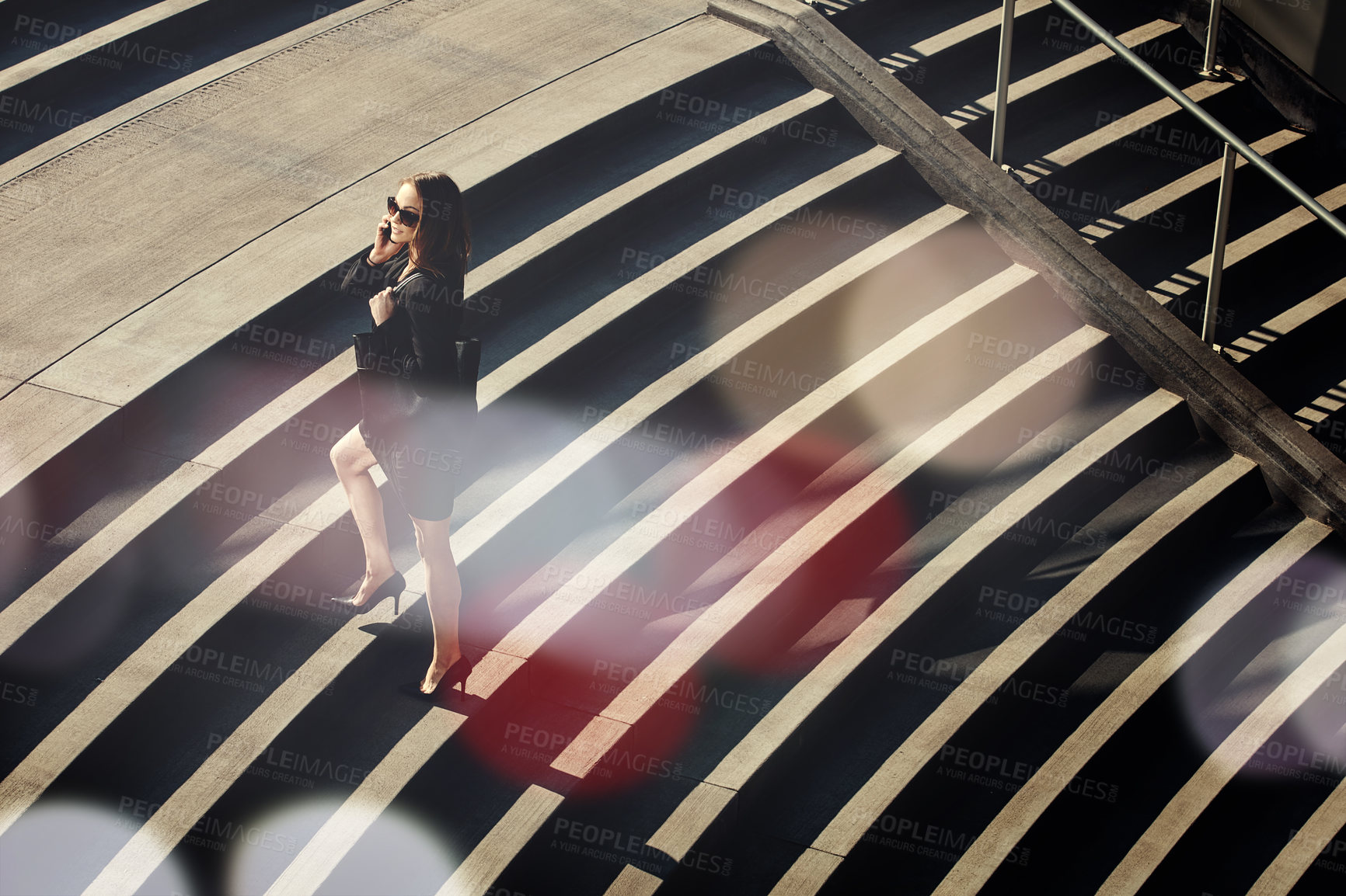 Buy stock photo Shot of a young businesswoman using a mobile phone while walking through the city