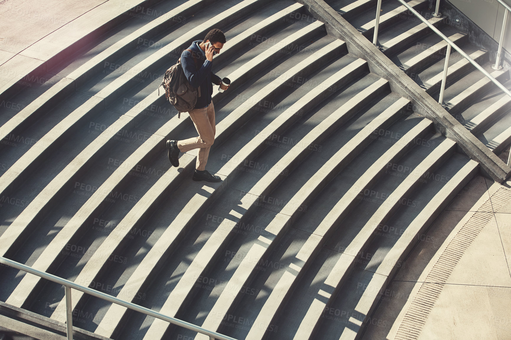 Buy stock photo Shot of a young businessman using a mobile phone while walking through the city