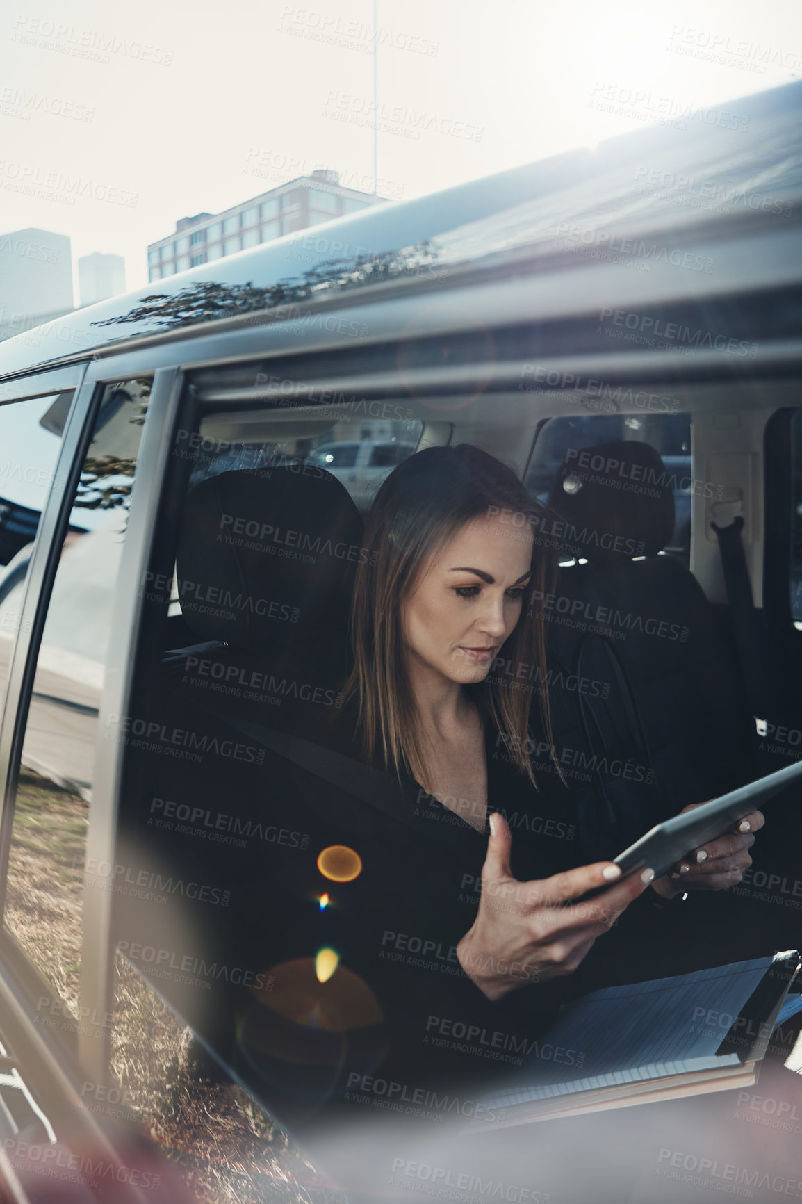 Buy stock photo Shot of a young businesswoman using a digital tablet while traveling in a car