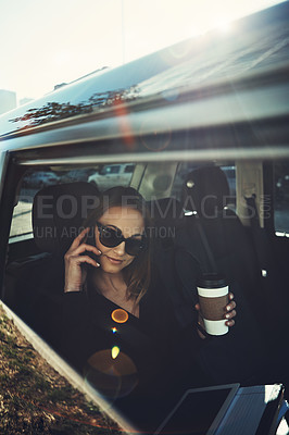 Buy stock photo Shot of a young businesswoman using a mobile phone while traveling in a car