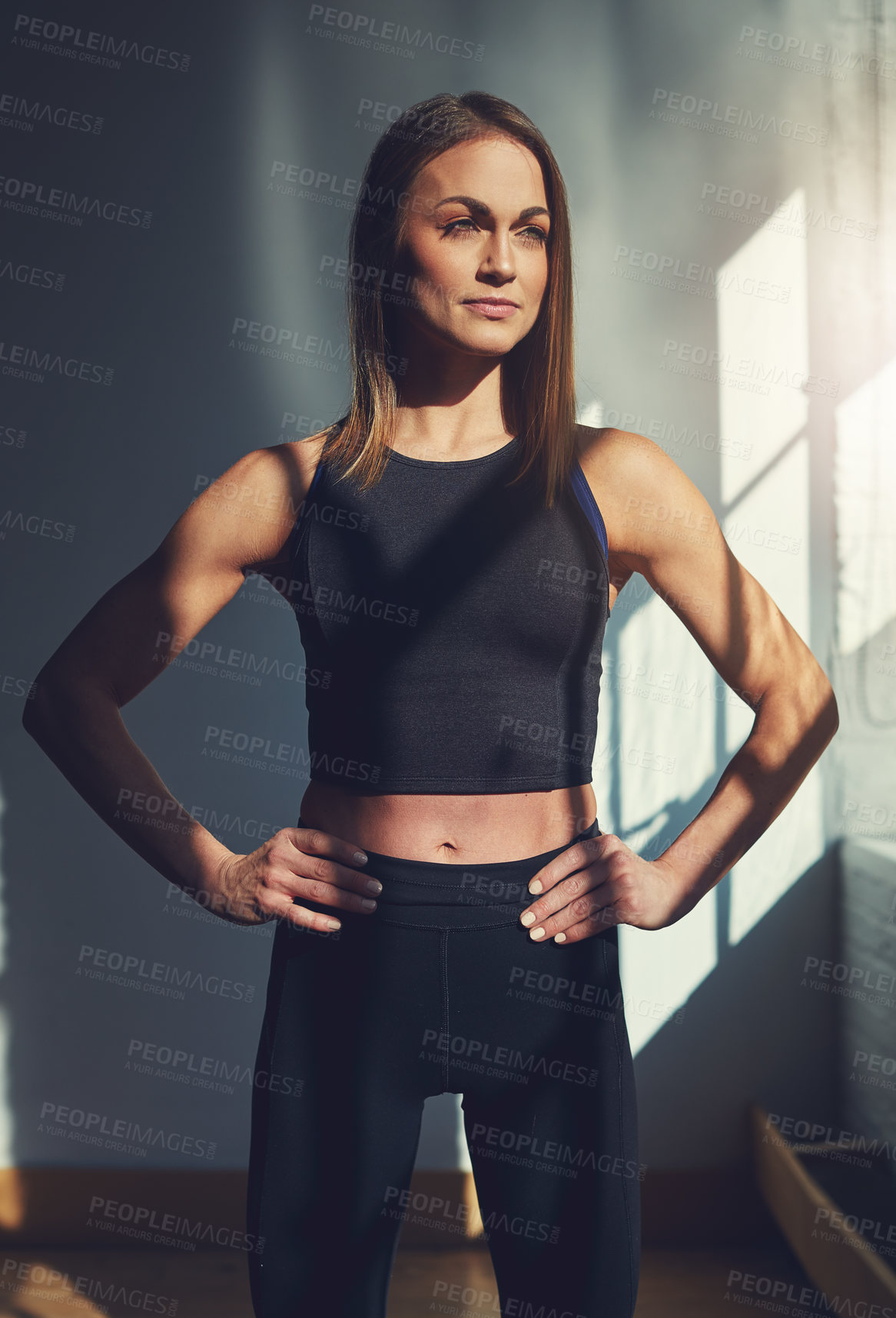 Buy stock photo Cropped shot of an attractive young sportswoman looking thoughtful while standing with her hands on her hips