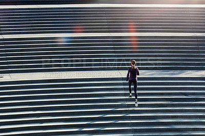 Buy stock photo High angle shot of an attractive young sportswoman running up and down stairs outside