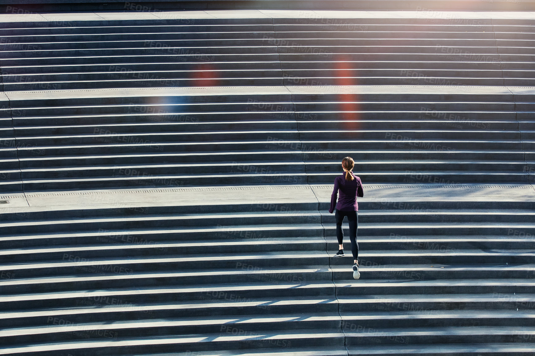 Buy stock photo High angle shot of an attractive young sportswoman running up and down stairs outside