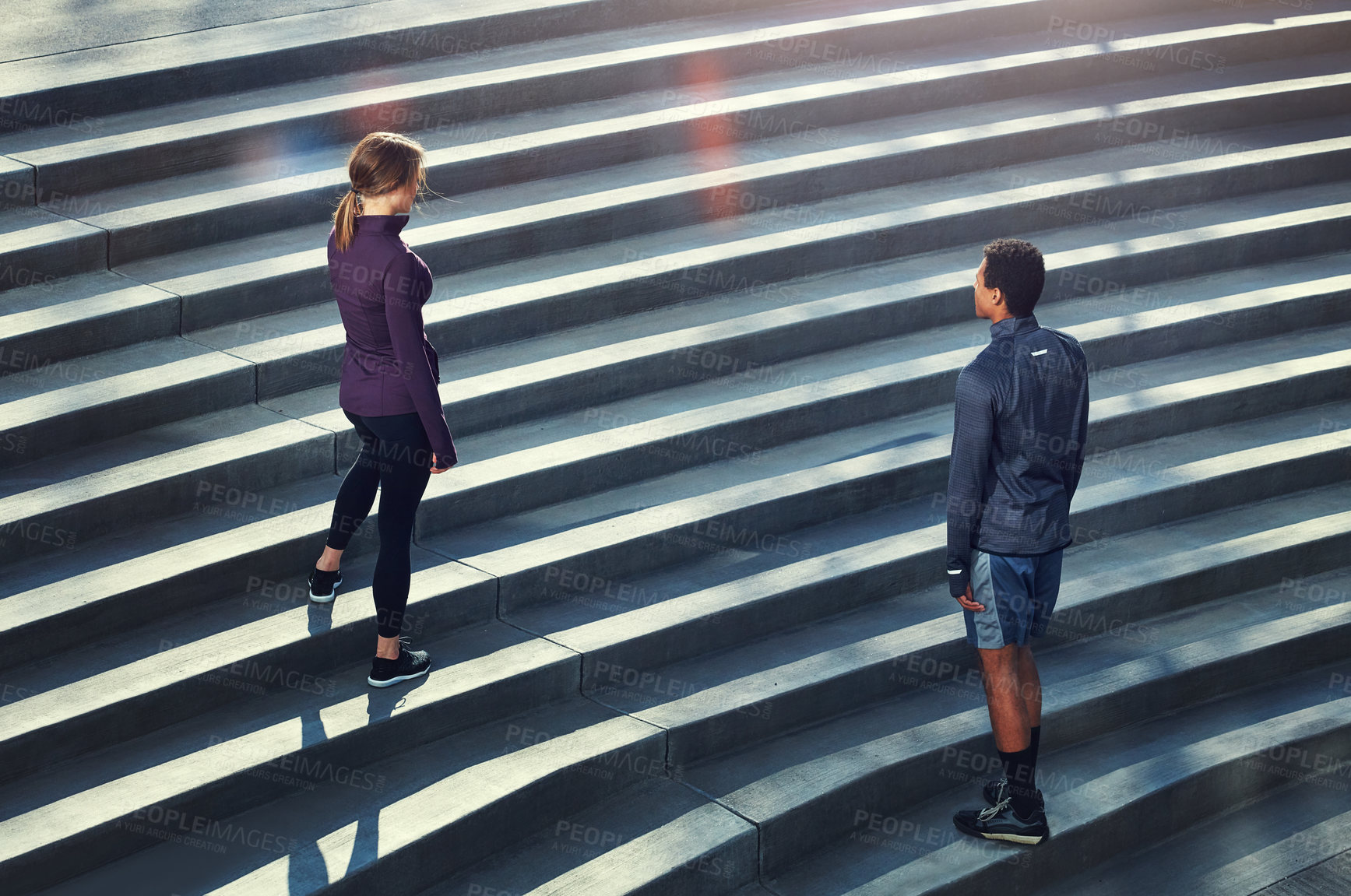 Buy stock photo High angle shot of two young sportspeople standing on stairs during their outdoor workout