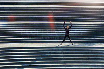 Buy stock photo High angle shot of an attractive young sportswoman doing jumping jacks on outside stairs
