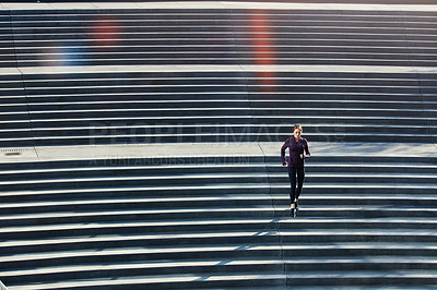 Buy stock photo High angle shot of an attractive young sportswoman running up and down stairs outside