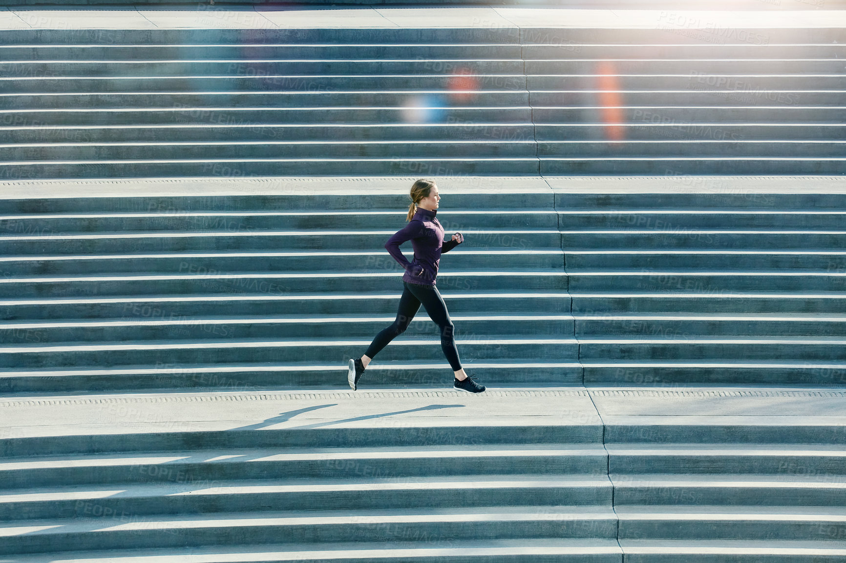 Buy stock photo Full length shot of an attractive young sportswoman running up and down stairs outside