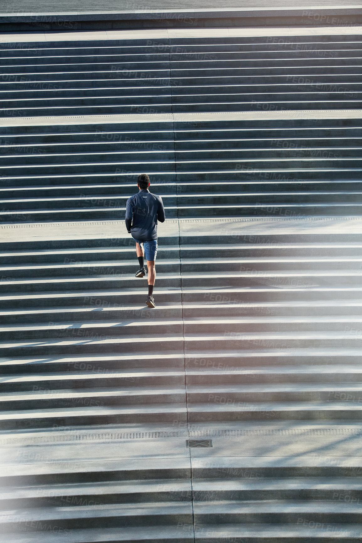 Buy stock photo High angle shot of a handsome young sportsman running up and down stairs outside