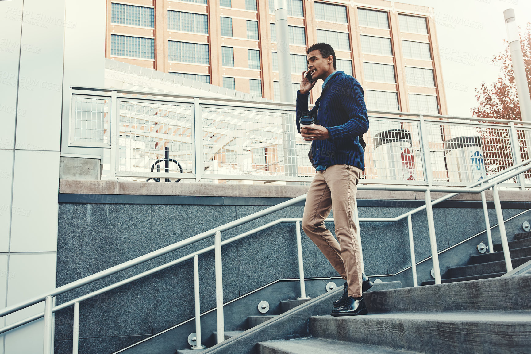 Buy stock photo Shot of a young businessman using a mobile phone while walking through the city