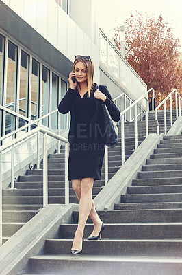 Buy stock photo Shot of a young businesswoman using a mobile phone while walking through the city