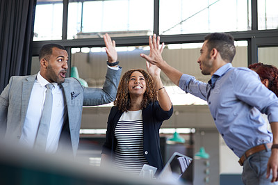 Buy stock photo Cropped shot of a group of young businesspeople high fiving while standing in the boardroom